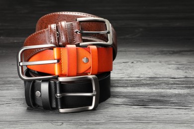 Photo of Three leather belts on wooden table, closeup. Space for text