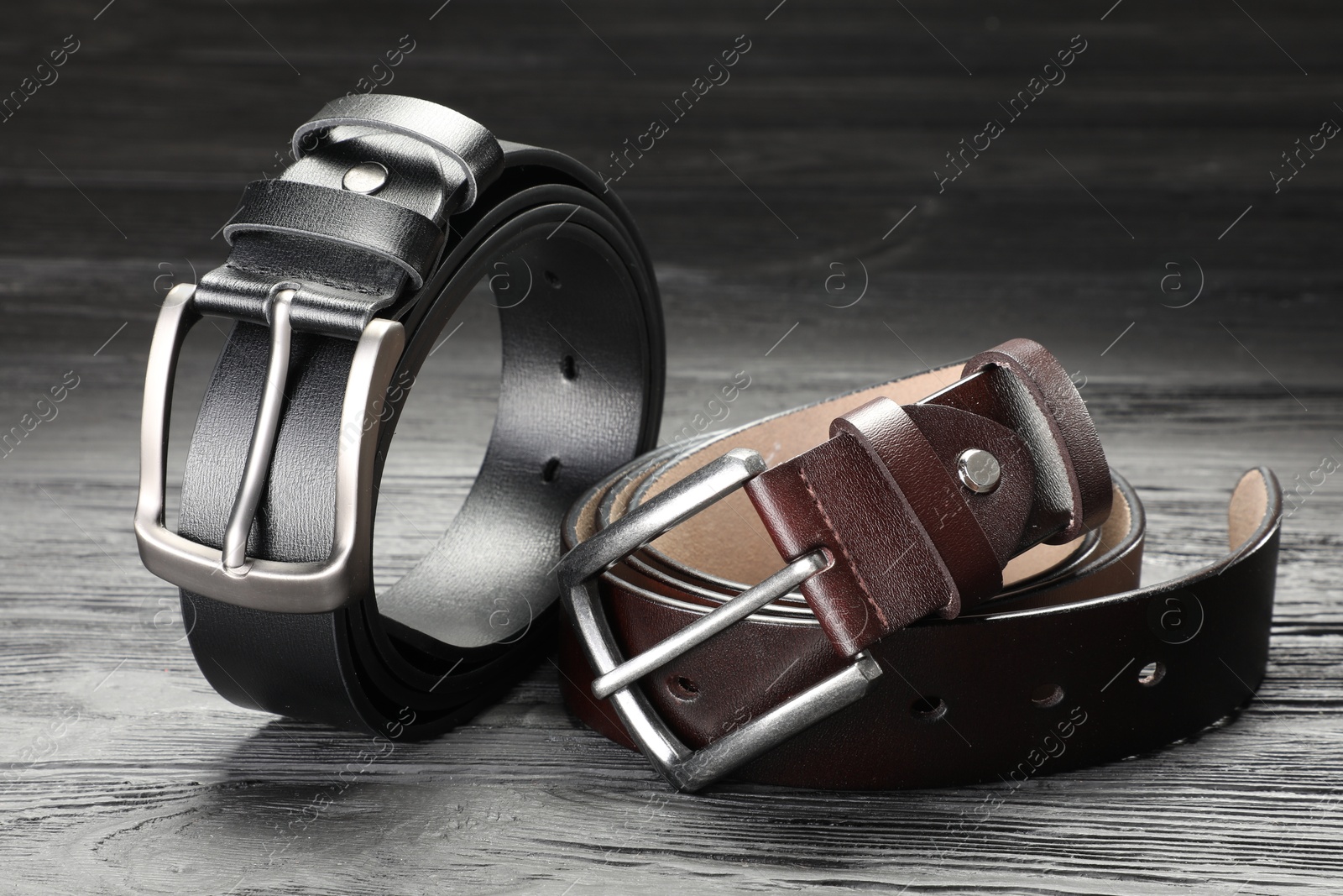 Two leather belts on wooden table, closeup Photo of Two leather belts on wooden table, closeup