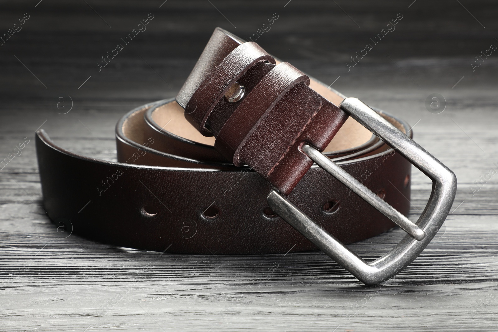 One brown leather belt on wooden table, closeup Photo of One brown leather belt on wooden table, closeup