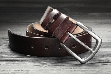 Photo of One brown leather belt on wooden table, closeup