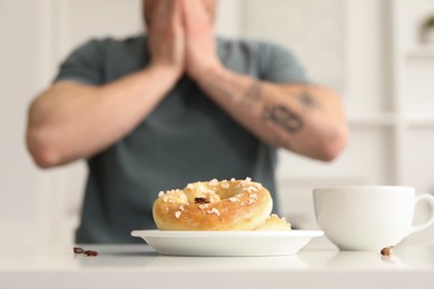 Photo of Shocked young man looking at cockroaches and pretzels on white table indoors, selective focus. Pest problem