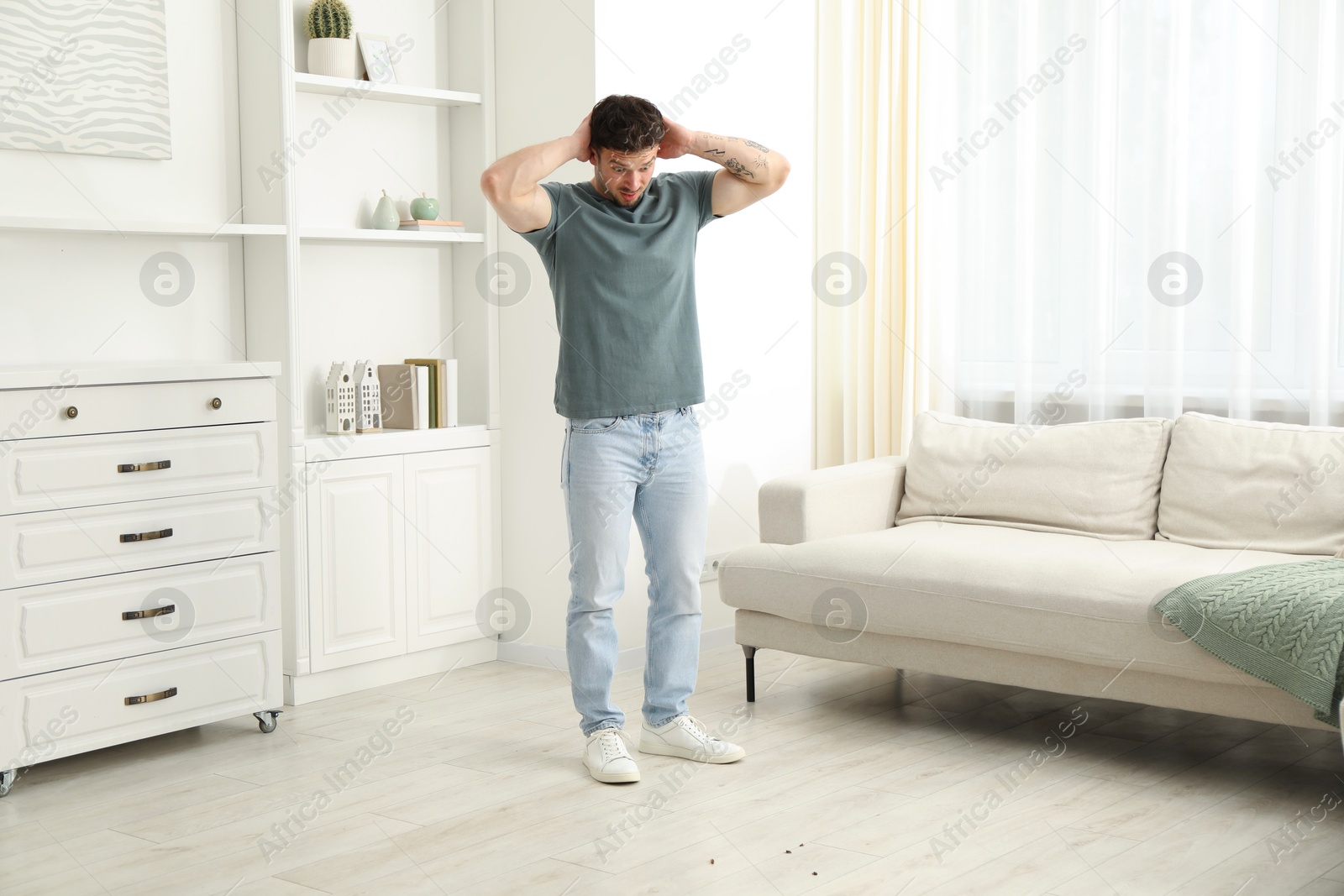 Emotional young man looking in disgust at cockroaches on floor indoors. Pest problem Photo of Emotional young man looking in disgust at cockroaches on floor indoors. Pest problem