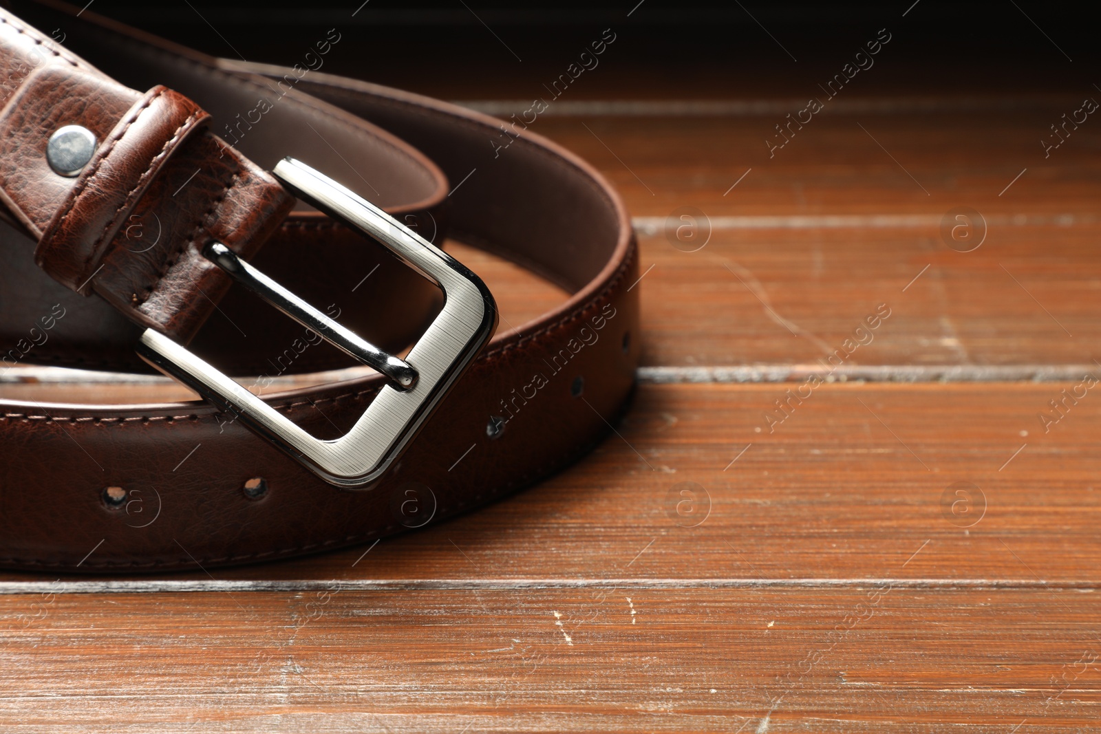 One brown leather belt on wooden table, closeup. Space for text Photo of One brown leather belt on wooden table, closeup. Space for text