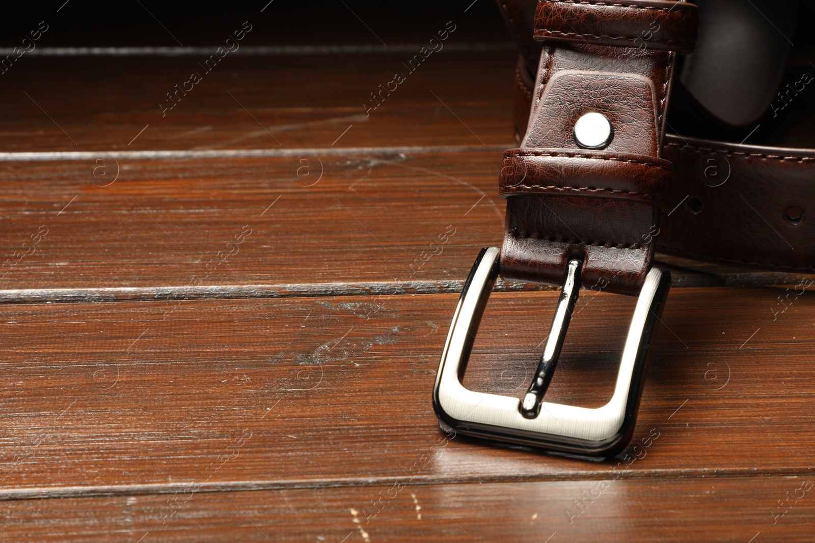 One brown leather belt on wooden table, closeup. Space for text Photo of One brown leather belt on wooden table, closeup. Space for text