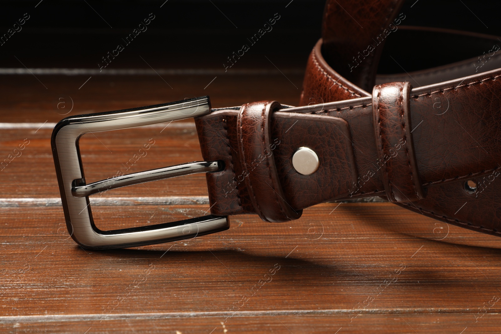 One brown leather belt on wooden table, closeup Photo of One brown leather belt on wooden table, closeup