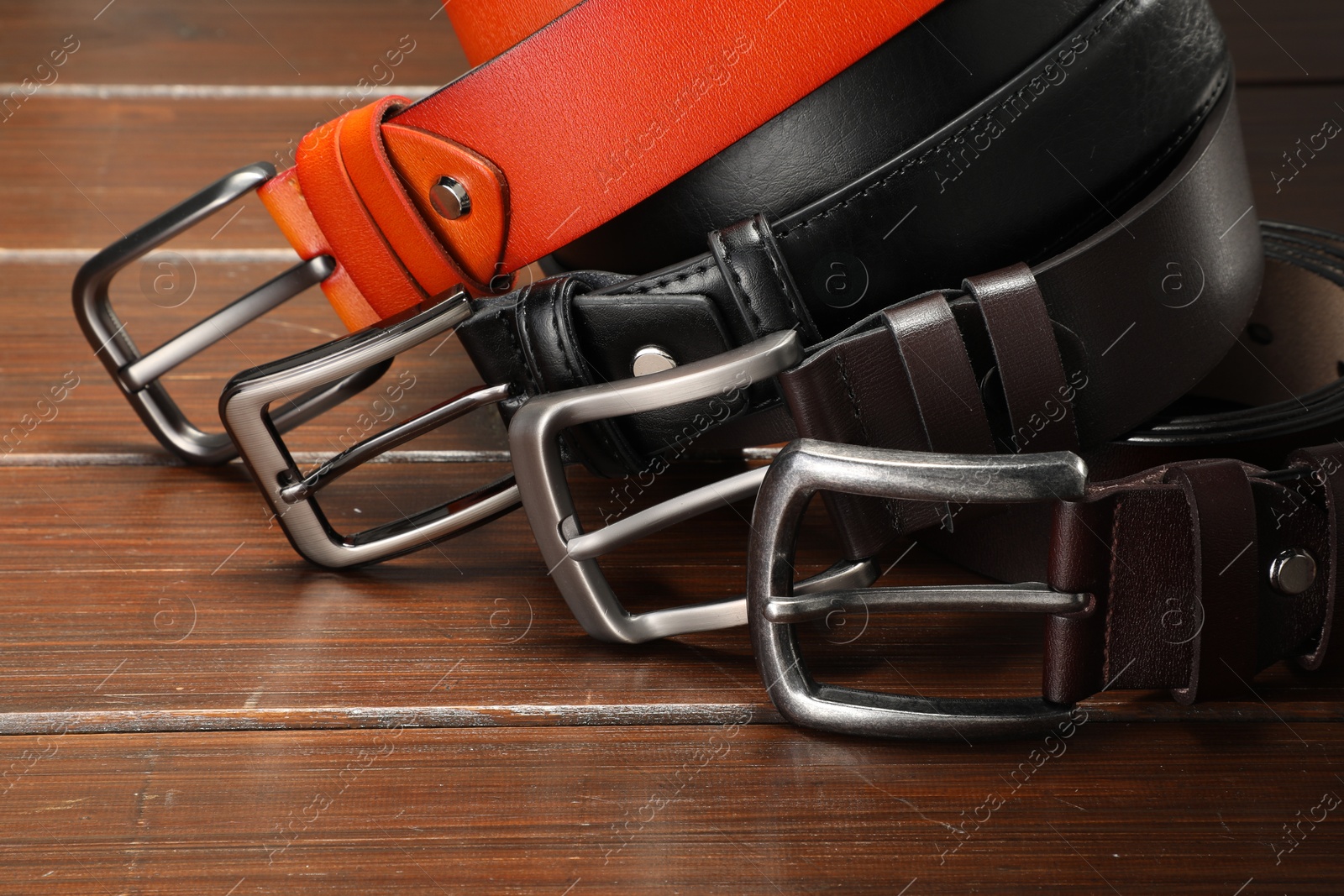 Many leather belts on wooden table, closeup Photo of Many leather belts on wooden table, closeup