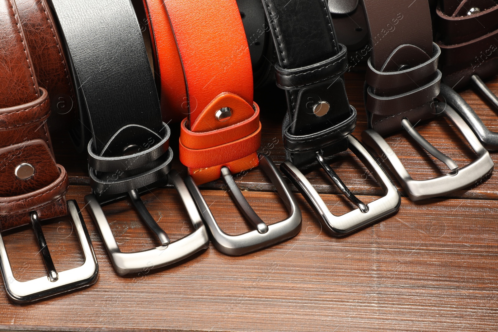 Many leather belts on wooden table, closeup Photo of Many leather belts on wooden table, closeup