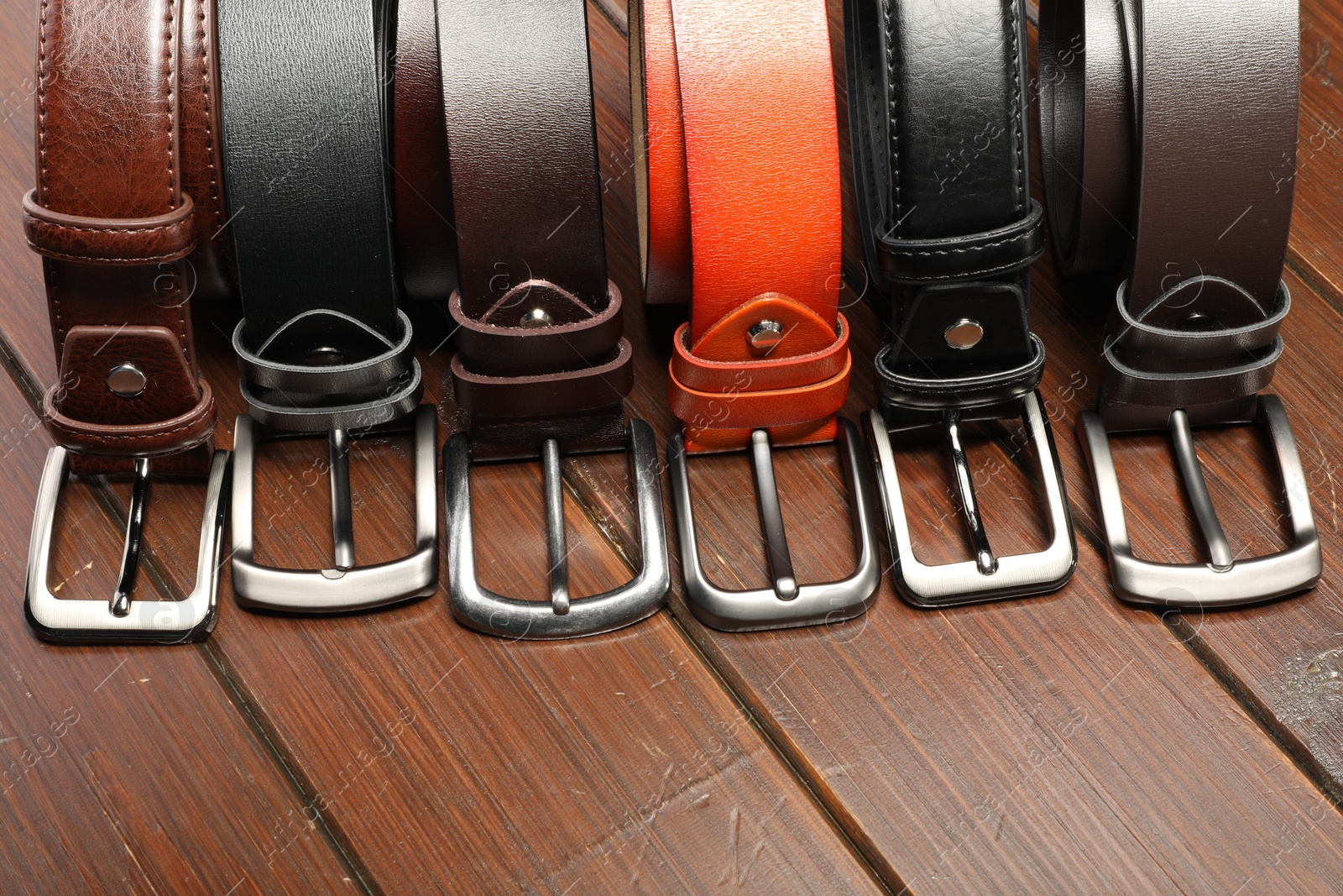 Many leather belts on wooden table, above view Photo of Many leather belts on wooden table, above view