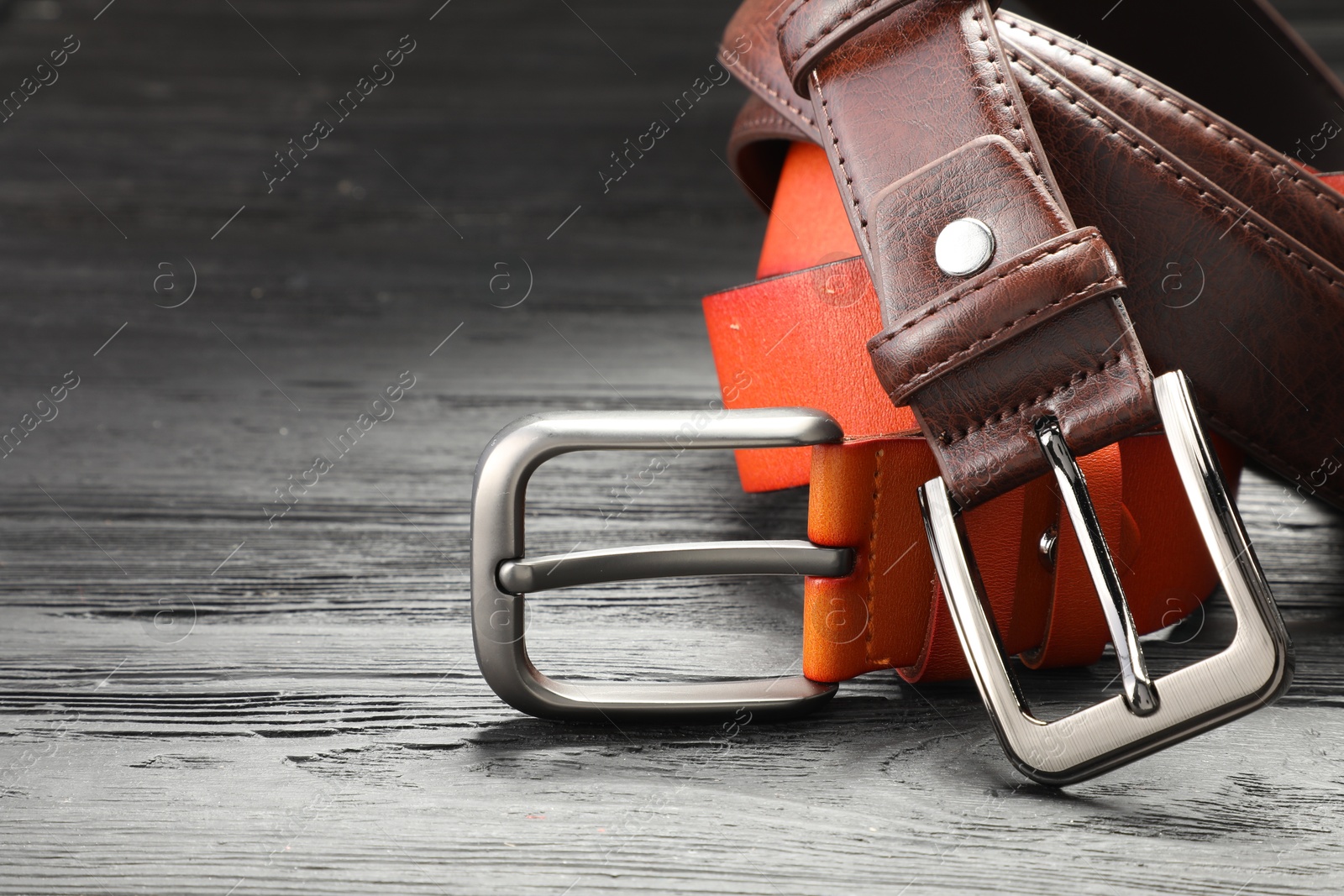 Two leather belts on wooden table, closeup. Space for text Photo of Two leather belts on wooden table, closeup. Space for text