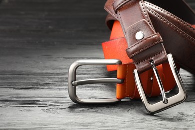 Photo of Two leather belts on wooden table, closeup. Space for text