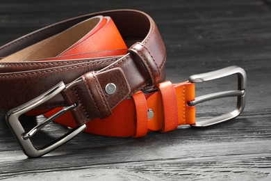 Photo of Two leather belts on wooden table, closeup