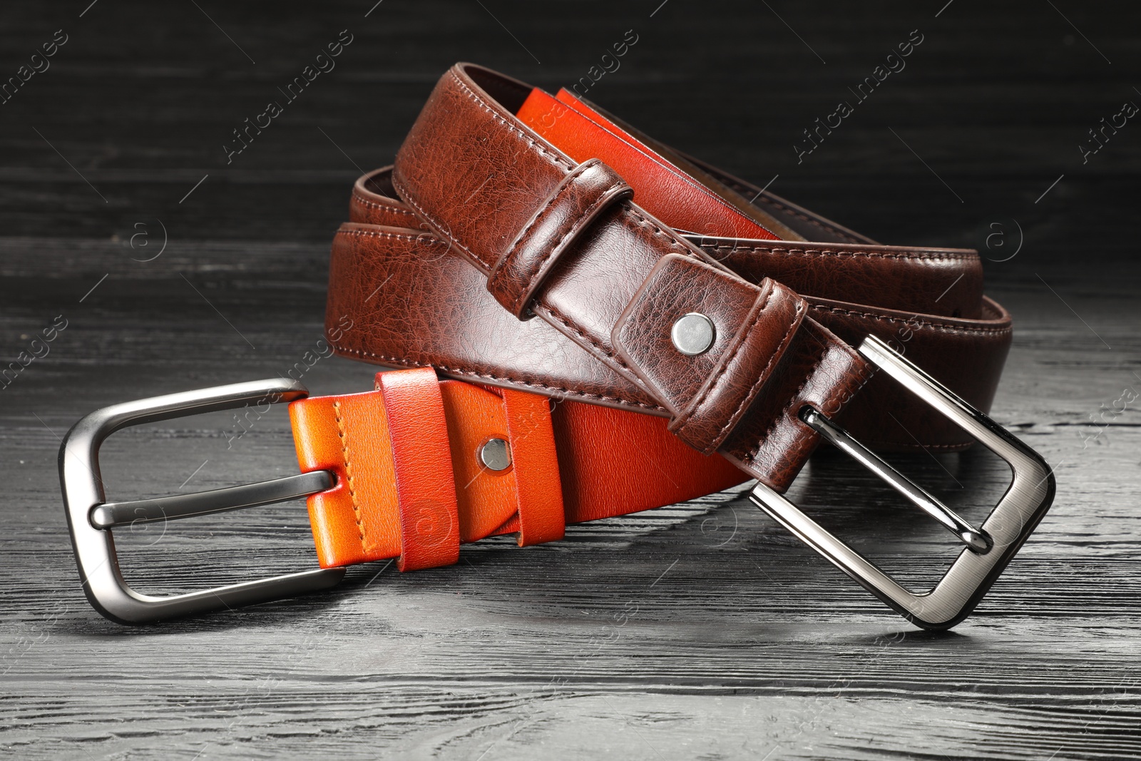 Two leather belts on wooden table, closeup Photo of Two leather belts on wooden table, closeup
