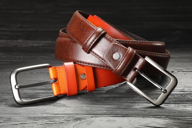 Photo of Two leather belts on wooden table, closeup