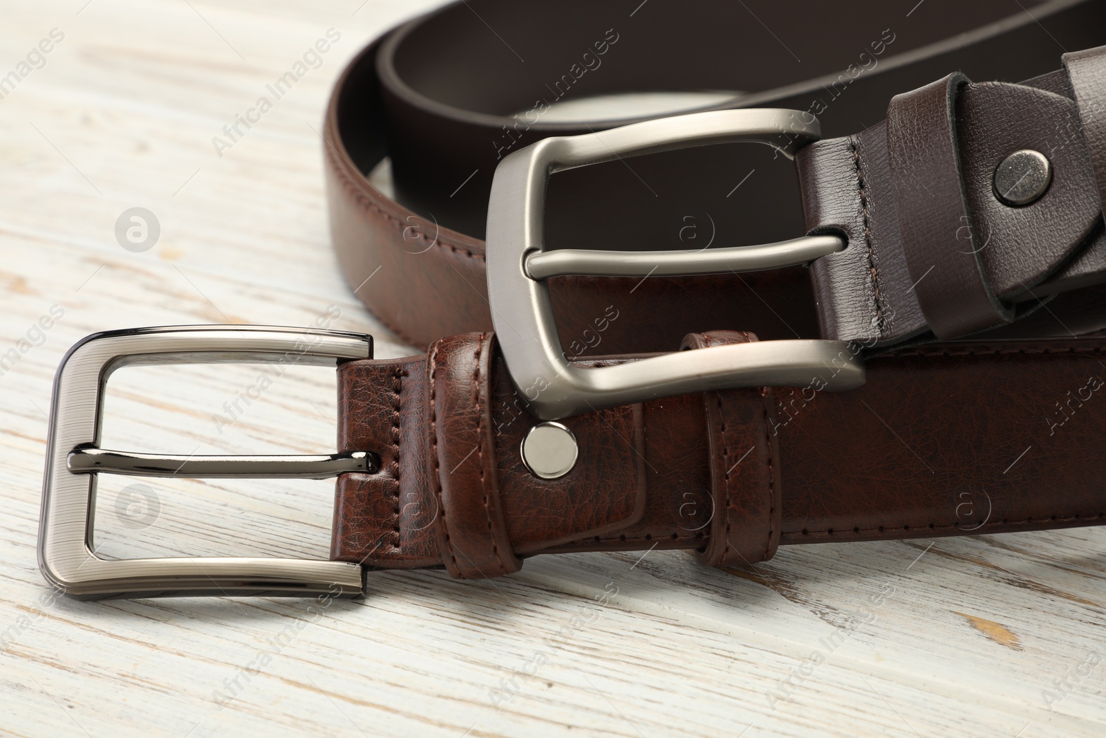 Two brown leather belts on wooden table, closeup Photo of Two brown leather belts on wooden table, closeup