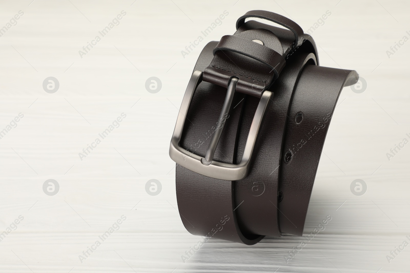 One brown leather belt on white wooden table, closeup. Space for text Photo of One brown leather belt on white wooden table, closeup. Space for text