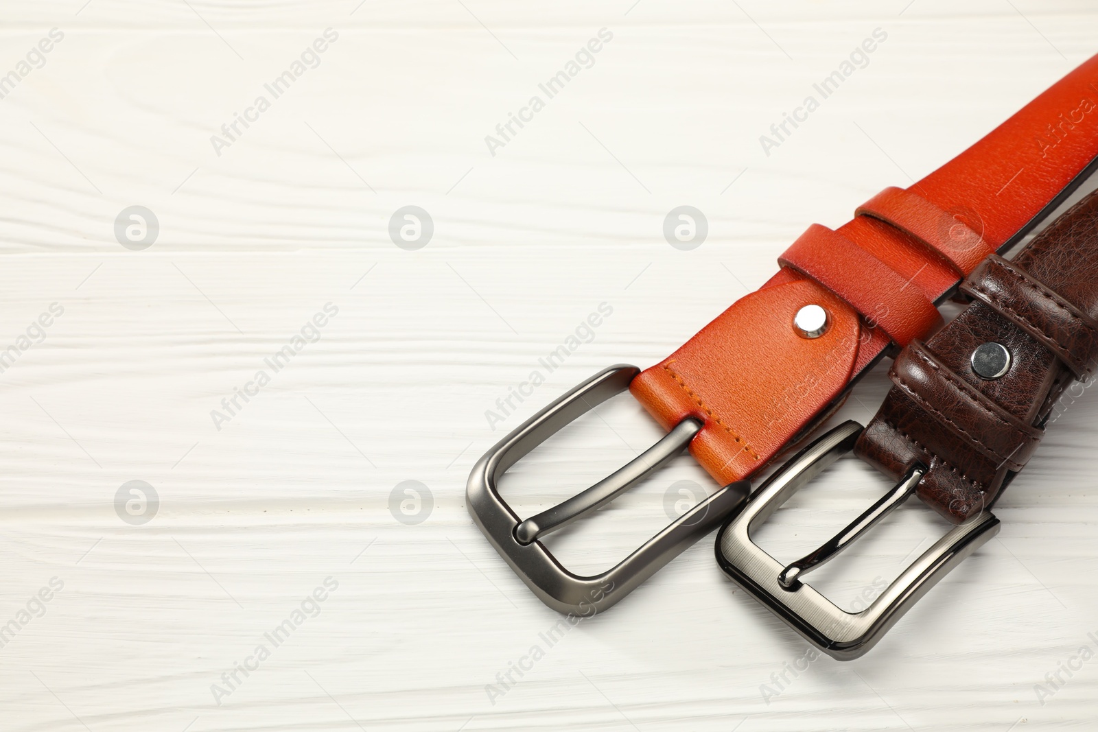 Two leather belts on white wooden table, above view. Space for text Photo of Two leather belts on white wooden table, above view. Space for text
