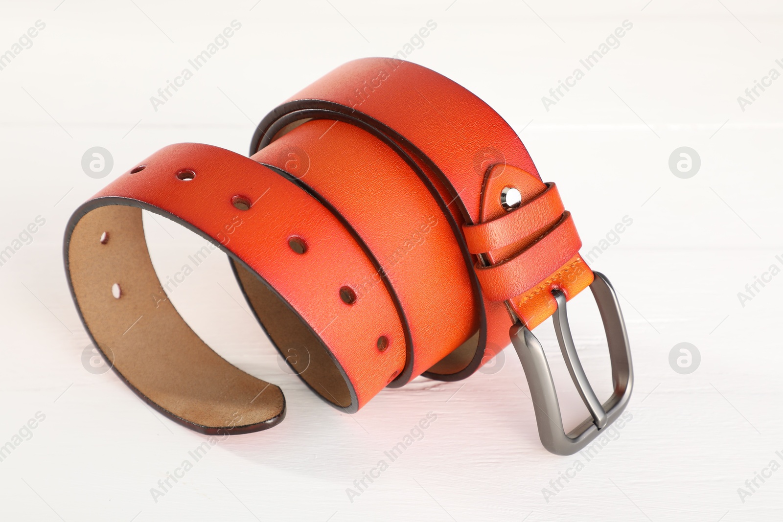 One orange leather belt on white wooden table, closeup Photo of One orange leather belt on white wooden table, closeup
