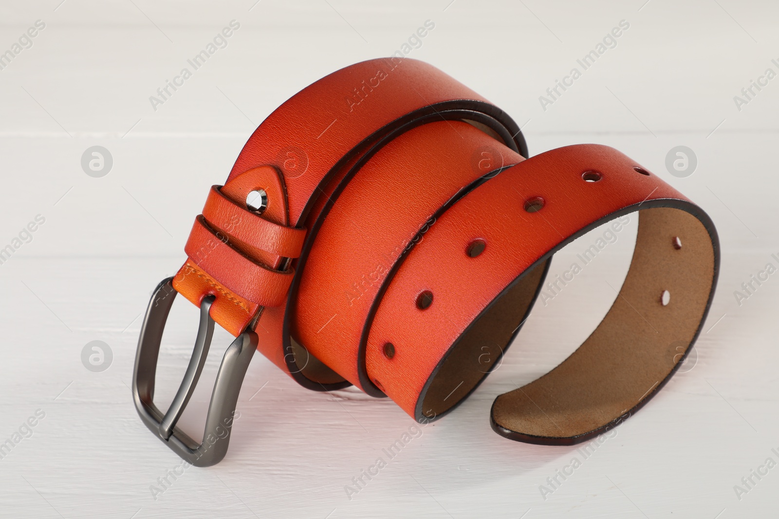 One orange leather belt on white wooden table, closeup Photo of One orange leather belt on white wooden table, closeup