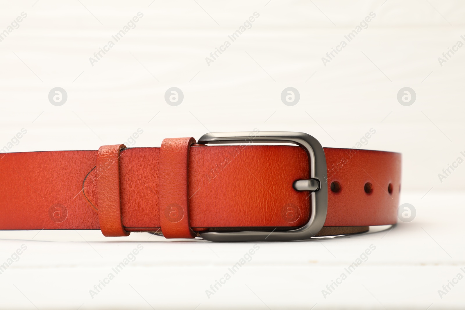 One orange leather belt on white table, closeup Photo of One orange leather belt on white table, closeup