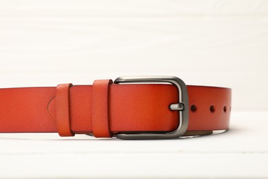 Photo of One orange leather belt on white table, closeup