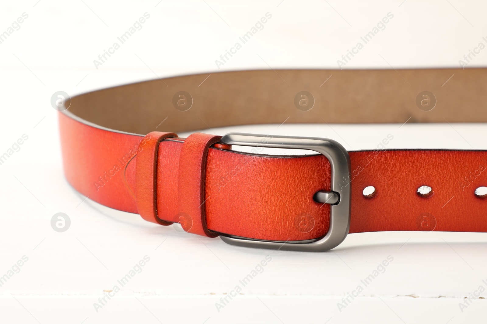 One orange leather belt on white table, closeup Photo of One orange leather belt on white table, closeup