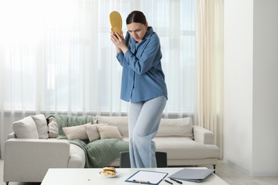Photo of Young woman with slipper looking in disgust at cockroaches on white table indoors. Pest problem