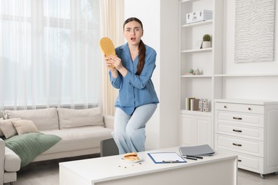 Photo of Young woman with slipper looking in disgust at cockroaches on white table indoors. Pest problem