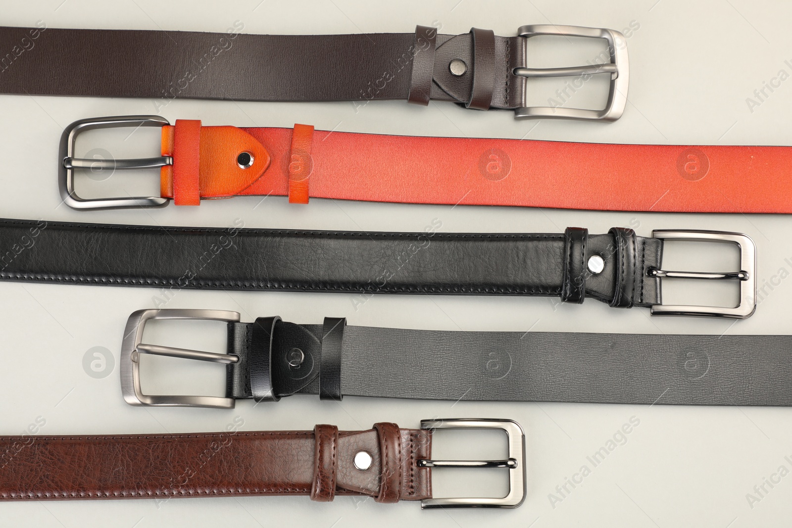 Many leather belts on white background, flat lay Photo of Many leather belts on white background, flat lay