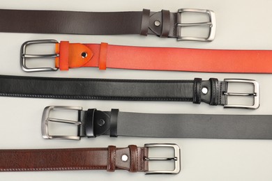 Photo of Many leather belts on white background, flat lay
