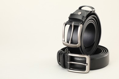 Photo of Two leather belts on white background, closeup. Space for text