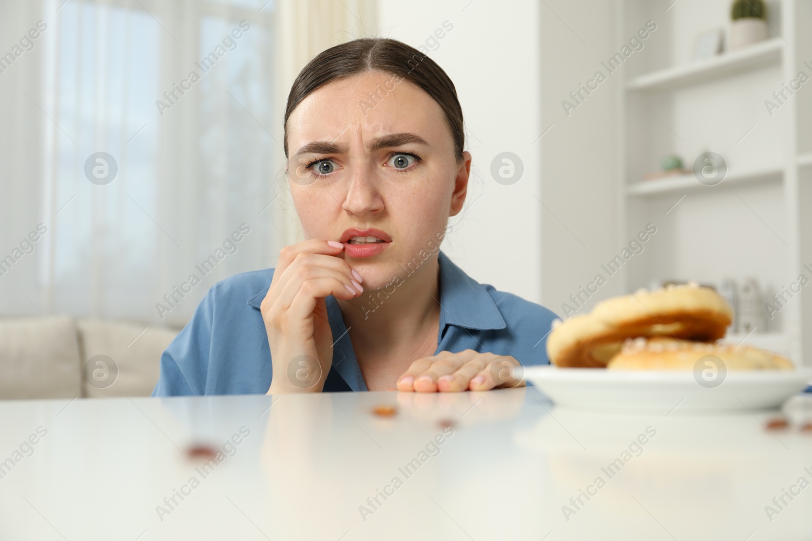 Shocked young woman looking at cockroaches and pretzels on white table indoors. Pest problem Photo of Shocked young woman looking at cockroaches and pretzels on white table indoors. Pest problem
