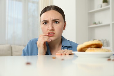 Photo of Shocked young woman looking at cockroaches and pretzels on white table indoors. Pest problem