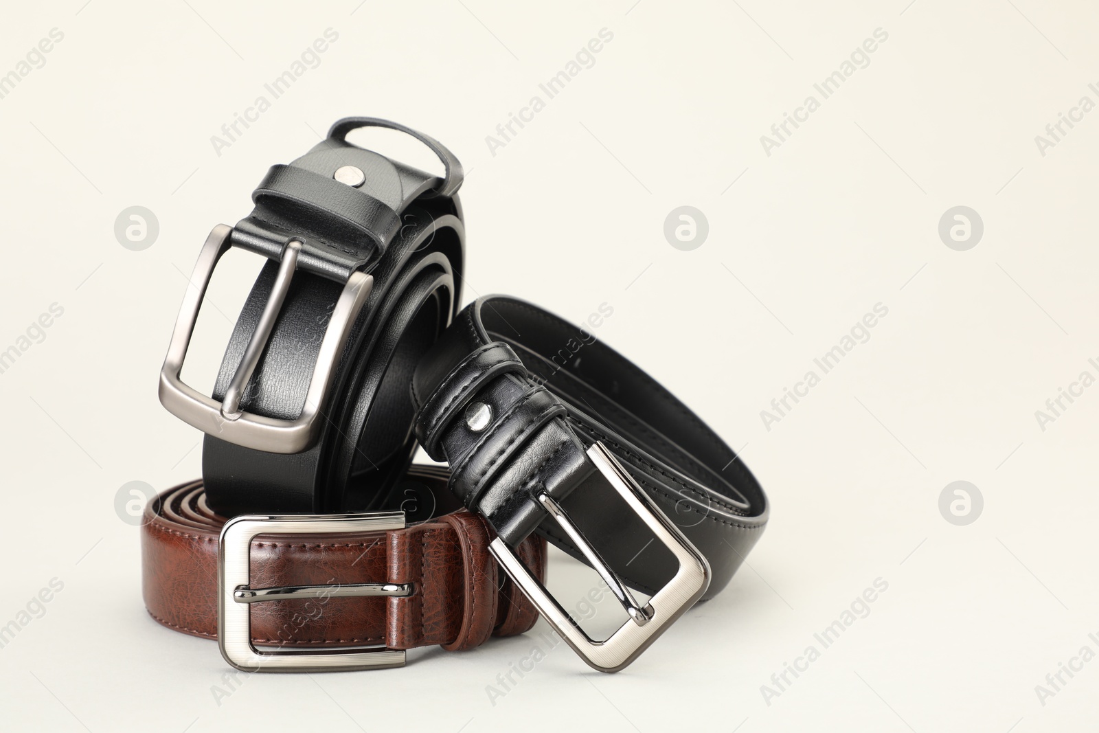 Three color leather belts on white background, space for text Photo of Three color leather belts on white background, space for text