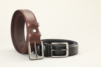 Photo of Two leather belts on white background, closeup