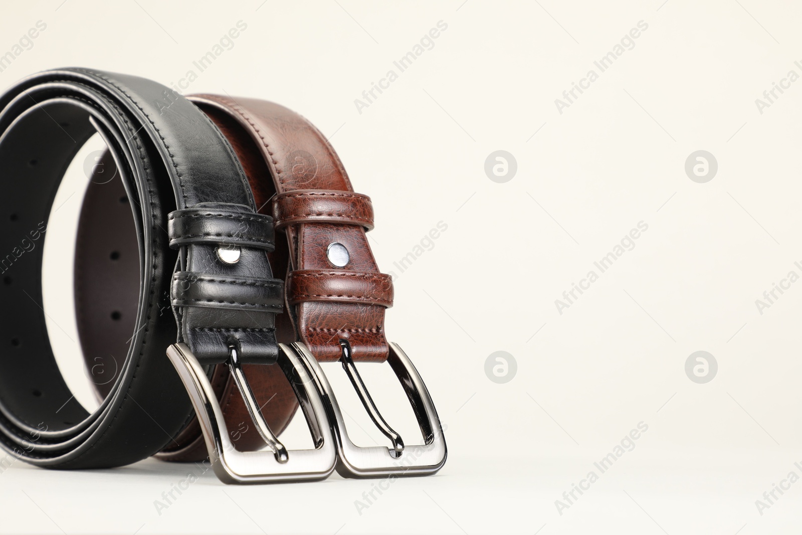 Two leather belts on white background, closeup. Space for text Photo of Two leather belts on white background, closeup. Space for text