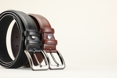 Photo of Two leather belts on white background, closeup. Space for text