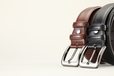 Photo of Two leather belts on white background, closeup. Space for text