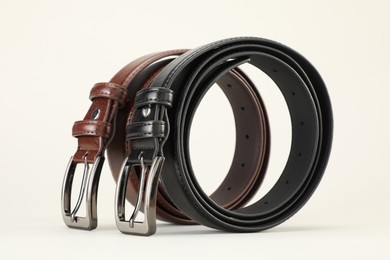 Photo of Two leather belts on white background, closeup