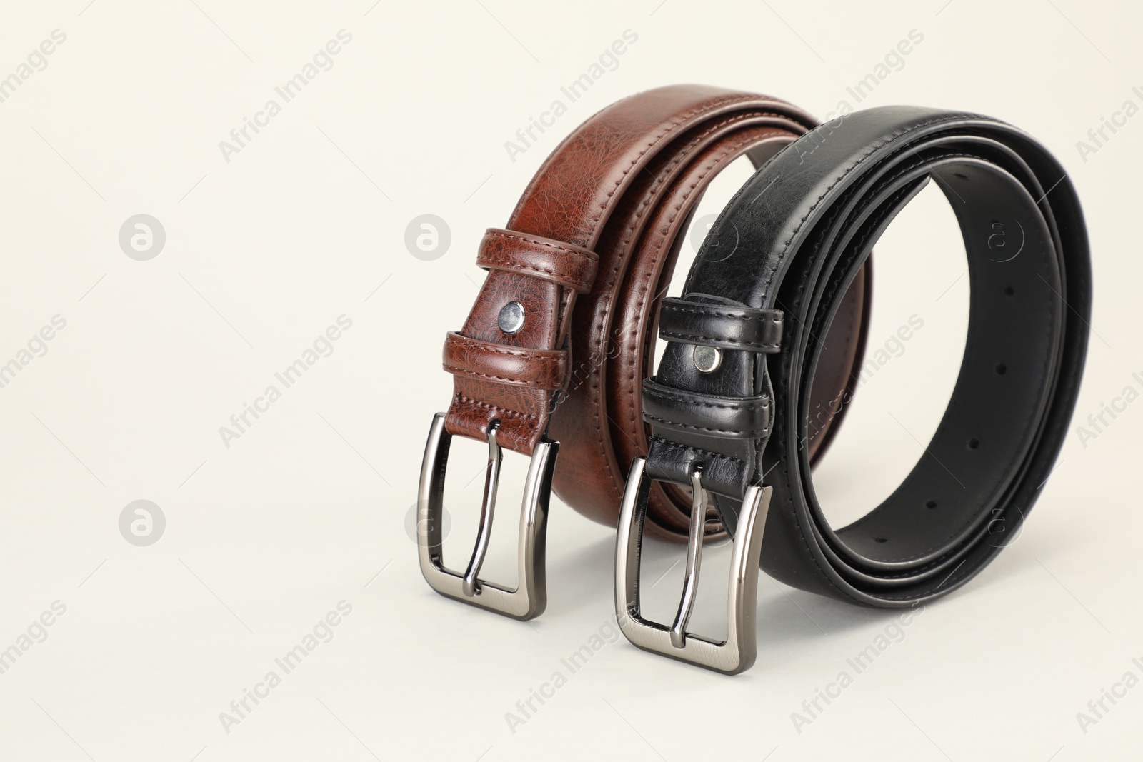 Two leather belts on white background, closeup. Space for text Photo of Two leather belts on white background, closeup. Space for text