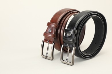 Photo of Two leather belts on white background, closeup. Space for text