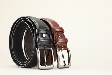 Photo of Two leather belts on white background, closeup. Space for text