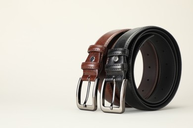 Photo of Two leather belts on white background, closeup. Space for text