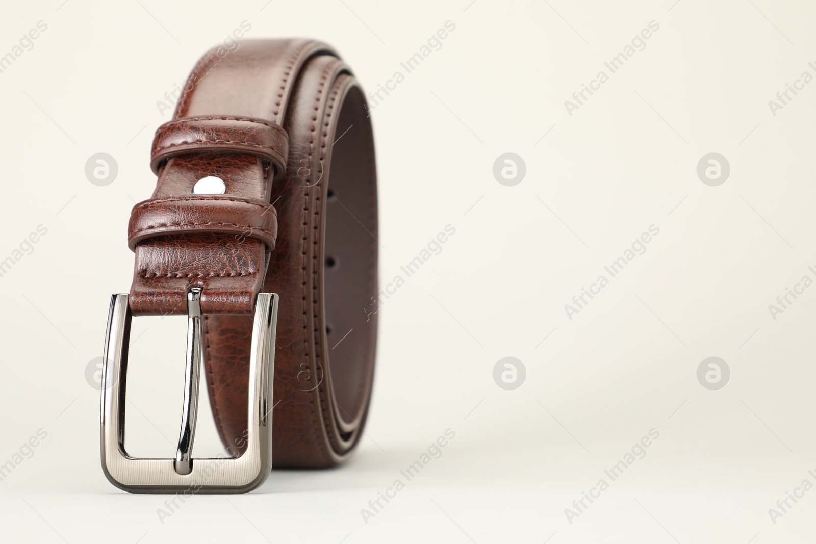 One brown leather belt on white background, closeup. Space for text Photo of One brown leather belt on white background, closeup. Space for text