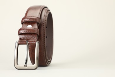 Photo of One brown leather belt on white background, closeup. Space for text