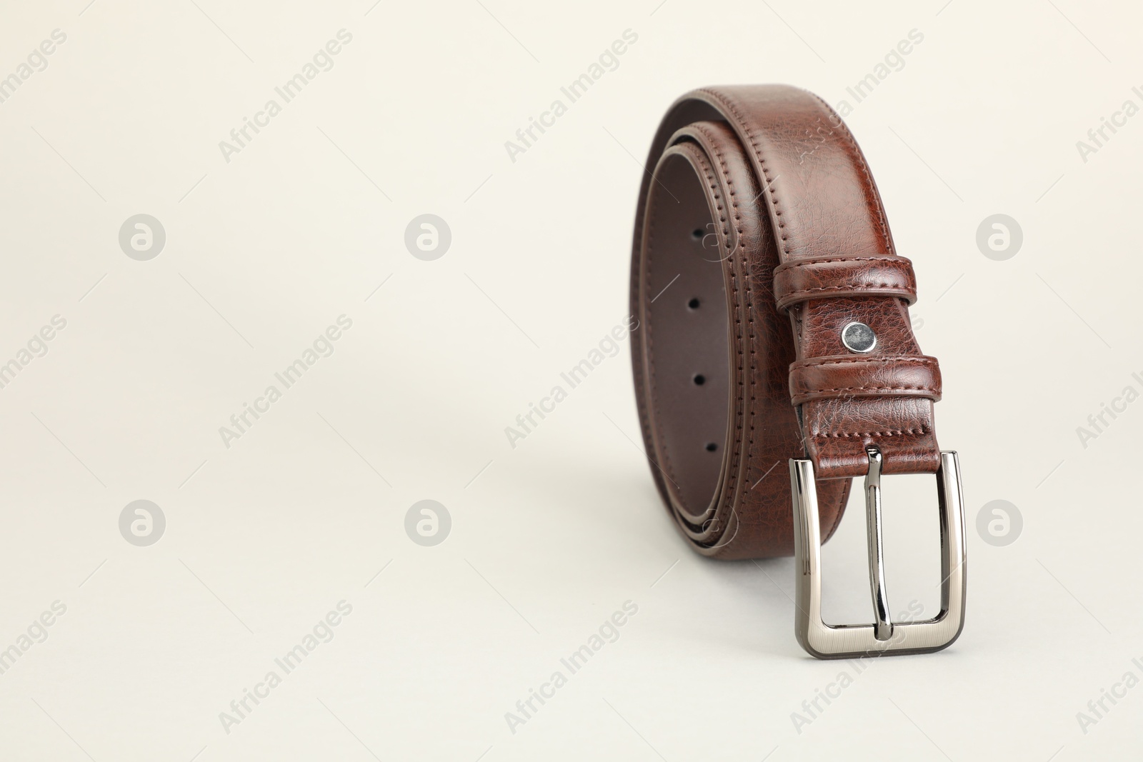 One brown leather belt on white background, closeup. Space for text Photo of One brown leather belt on white background, closeup. Space for text