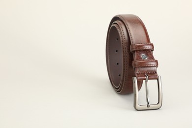 Photo of One brown leather belt on white background, closeup. Space for text