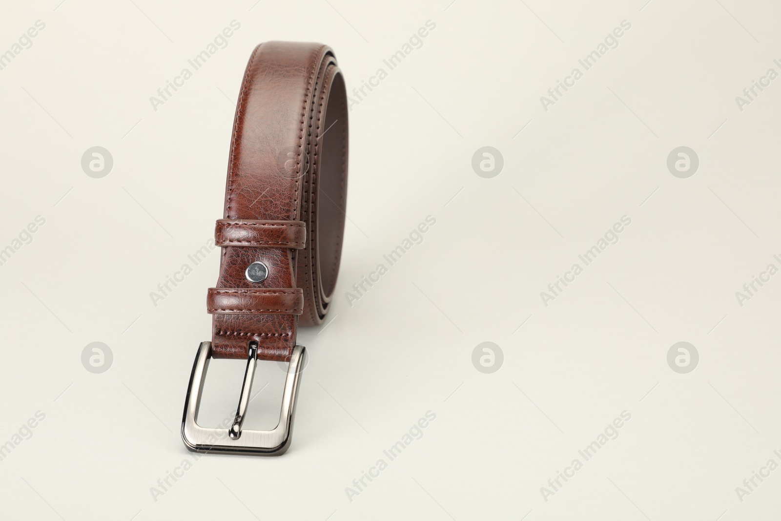One brown leather belt on white background, closeup. Space for text Photo of One brown leather belt on white background, closeup. Space for text