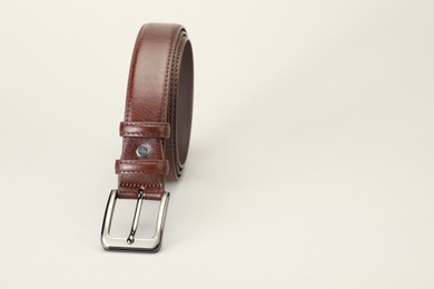 Photo of One brown leather belt on white background, closeup. Space for text