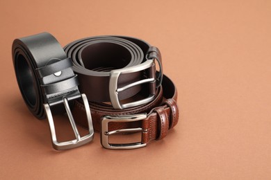 Photo of Three leather belts on pale brown background, space for text