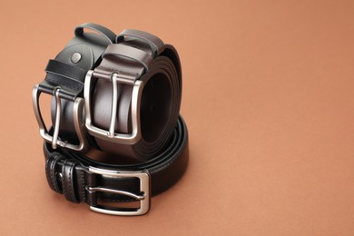 Photo of Three leather belts on pale brown background, space for text